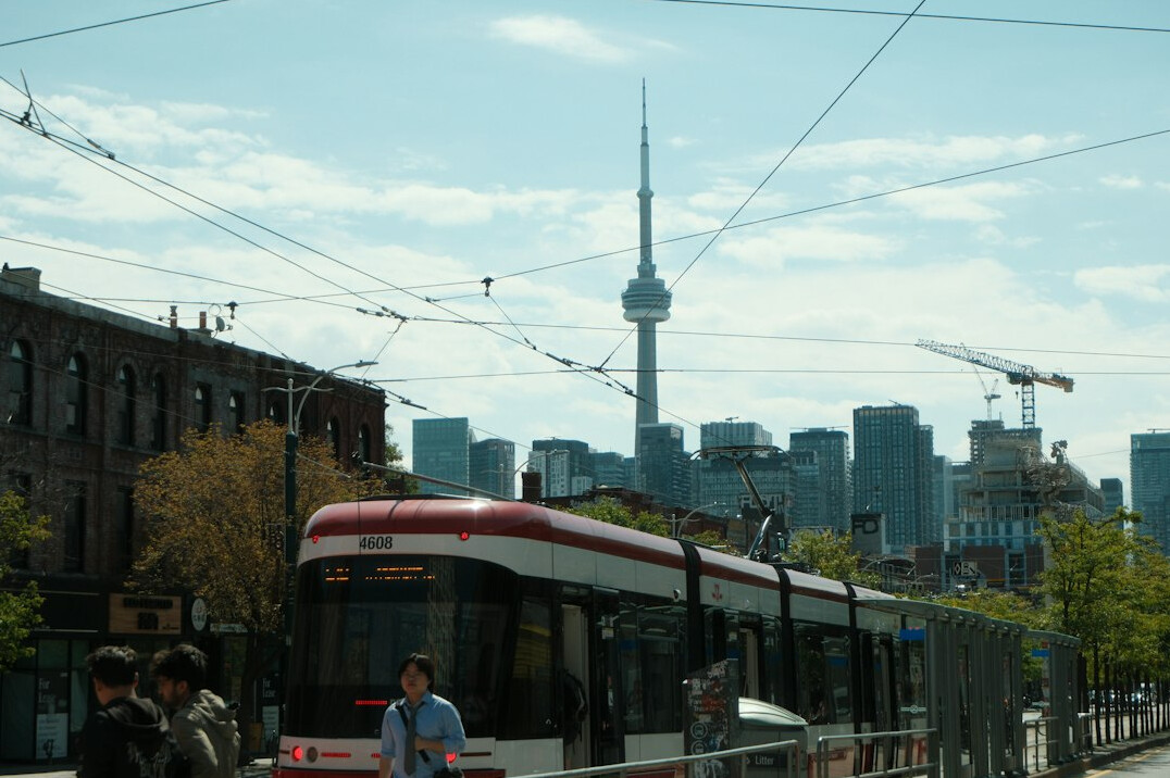 Streetcar and pedestrians on a downtown Toronto avenue lined with old brick buildings
